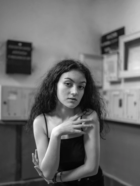 a black and white photo of a woman in a room, inspired by irakli nadar, pexels contest winner, antipodeans, at the counter, curly black hair, teenage girl, sitting in a waiting room