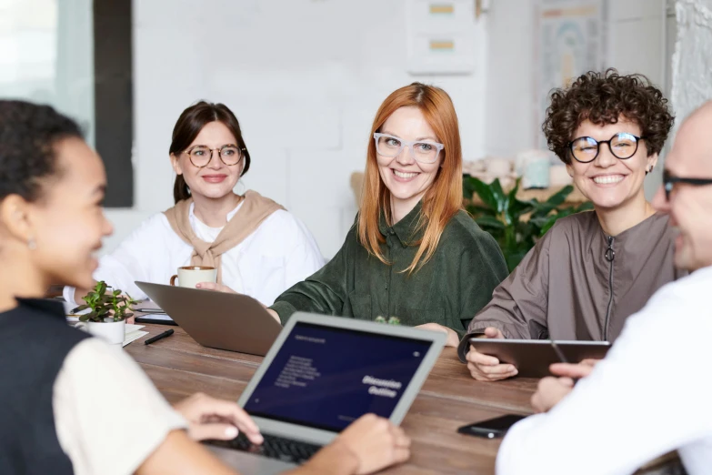 a group of people sitting around a table with laptops, by Nicolette Macnamara, trending on pexels, wearing small round glasses, hr ginger, school curriculum expert, decoration