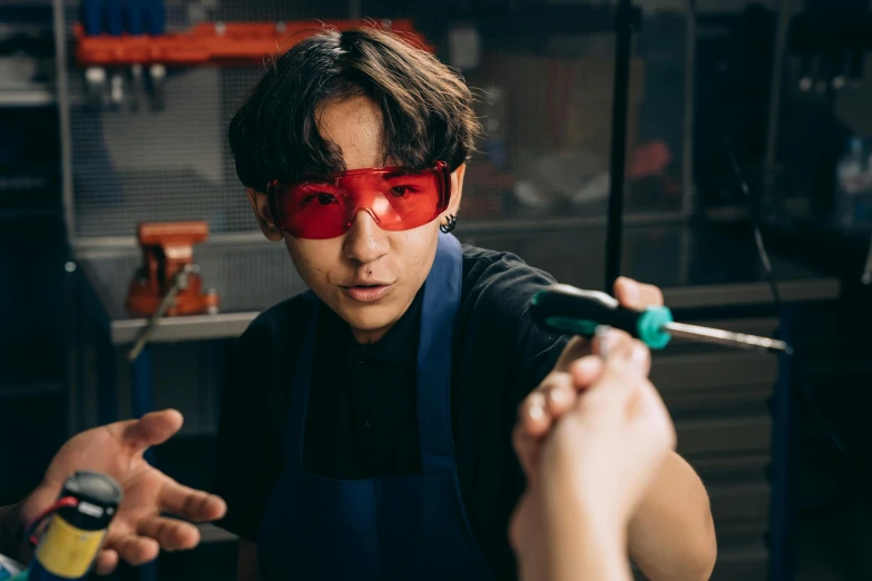 a close up of a person wearing a pair of red glasses, process art, welding torches for arms, male teenager, experimenting in her science lab, lachlan bailey