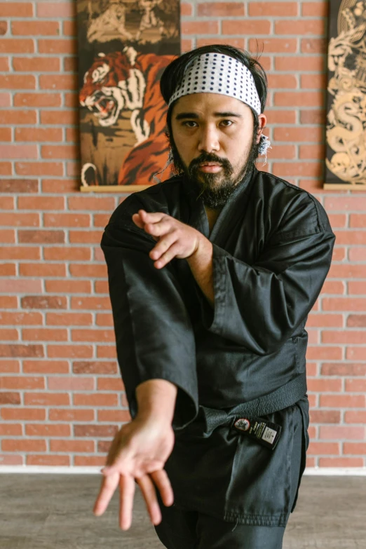 a man standing in front of a brick wall, inspired by Kanō Shōsenin, martial arts tournament, portrait of danny gonzalez, promotional image