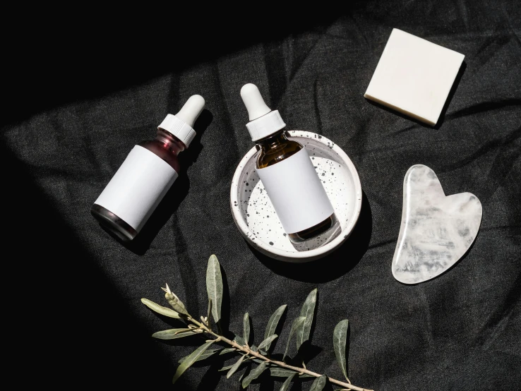 a couple of bottles sitting on top of a table, by Julia Pishtar, trending on pexels, small vials and pouches on belt, black oil bath, eucalyptus, her face is coated in a white