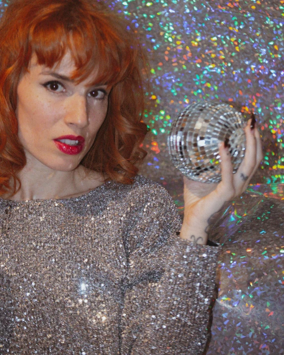 a woman with red hair holding a disco ball, inspired by Leila Faithfull, wearing! robes!! of silver, non binary model, sparkly