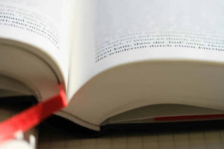 a close up of an open book with a red ribbon, unsplash, reading engineering book, rounded corners, thumbnail, looking towards camera