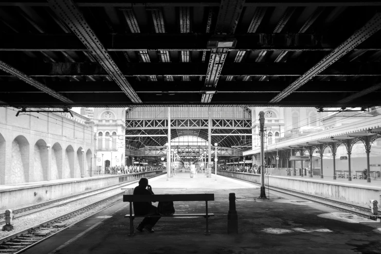 a black and white photo of a person sitting on a bench, central station in sydney, in the middle of new york, taken in 2 0 2 0, wooden platforms