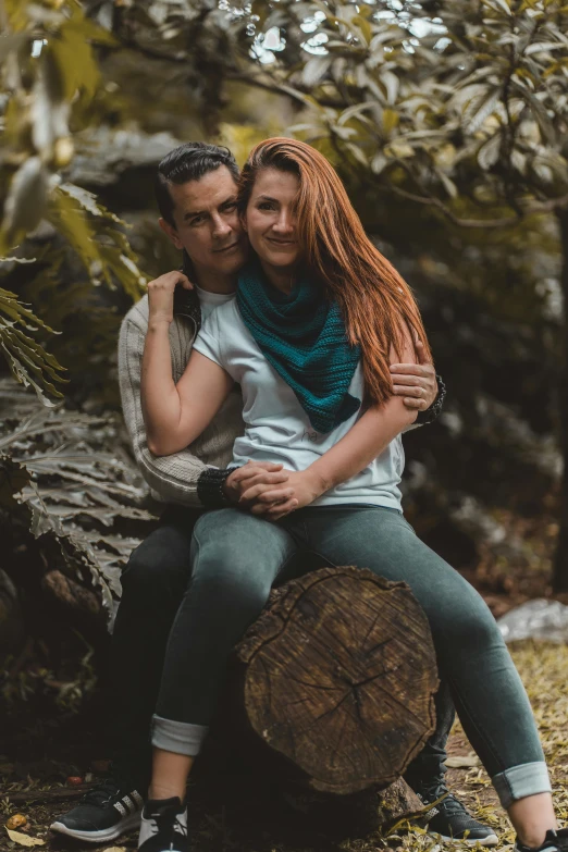 a man and woman sitting on a log in the woods, a colorized photo, by Alejandro Obregón, pexels contest winner, wild ginger hair, hug, chile, indoor picture