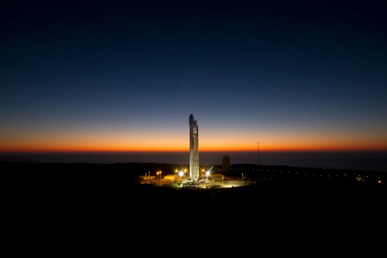 a rocket that is sitting on top of a hill, a picture, by Josh Bayer, happening, spaceport docking bay at night, sunrise lighting, mantis, nasa photo