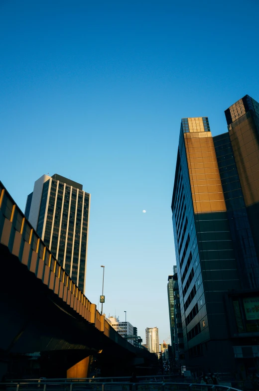 a couple of tall buildings sitting next to each other, an album cover, unsplash, brutalism, with the moon out, manchester, sky bridge, long street