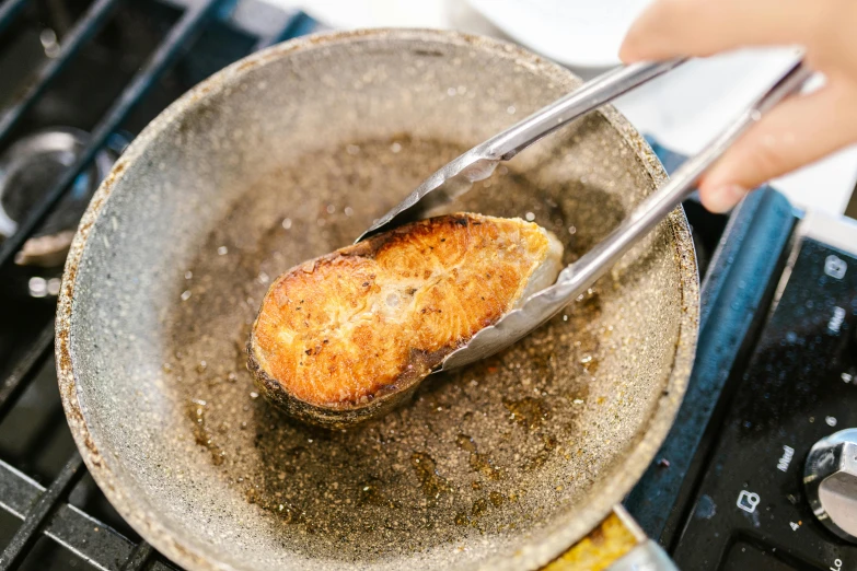 a person frying a piece of bread in a frying pan, by Joe Bowler, unsplash, mingei, fish skin, manuka, made of glazed, thumbnail