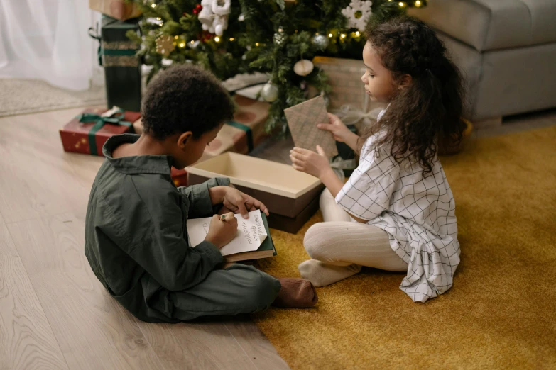 two children sitting on the floor in front of a christmas tree, pexels contest winner, visual art, holding spell book, green and brown clothes, looking around a corner, educational supplies