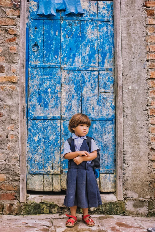 a little boy standing in front of a blue door, pexels contest winner, quito school, girl wearing uniform, dressed in a worn, 4yr old, a handsome