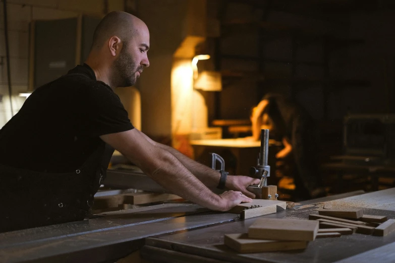 a man is working on a piece of wood, by Lee Loughridge, pexels contest winner, arbeitsrat für kunst, night time low light, 9 9 designs, profile picture, rectangle