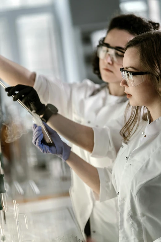 a couple of women standing next to each other in a lab, by Adam Marczyński, shutterstock, instagram post, student, glazing, plating