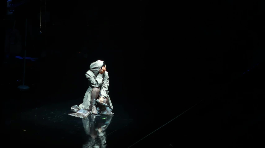 a woman in a white dress on a stage, a hologram, by Caro Niederer, unsplash, holography, wearing sci - fi cloak with hood, björk, a dark underwater scene, production photo