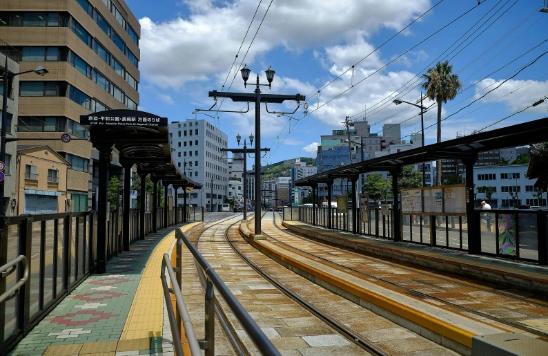 a train traveling down train tracks next to tall buildings, unsplash, sōsaku hanga, square, nagasaki, cart, 2022 photograph