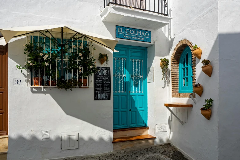 a white building with a blue door and window, restaurant, la catrina, small path up to door, profile image