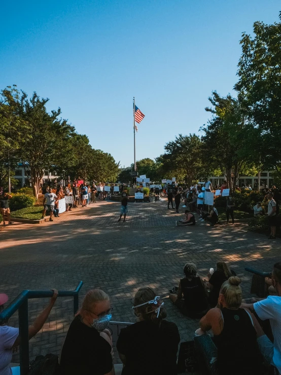 a crowd of people sitting on the side of a road, bentonville arkansas, in a city square, shut down, 2022 photograph