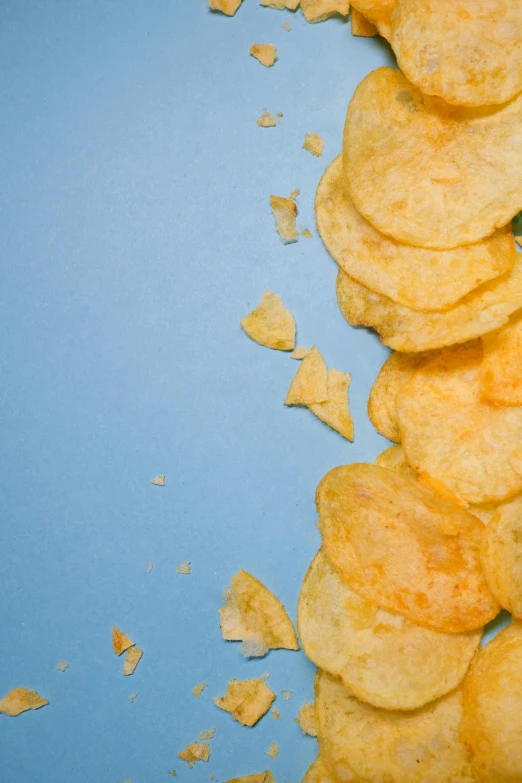 a pile of potato chips on a blue surface, inspired by Chippy, pexels, square, cheeses, soft shade, hillside