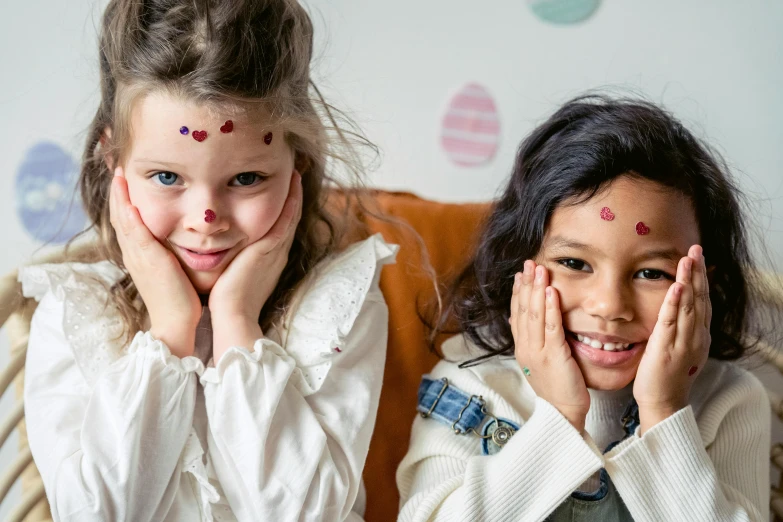 a couple of young girls sitting next to each other, by Emma Andijewska, pexels, jeweled ornament over forehead, easter, ink dots, stickers