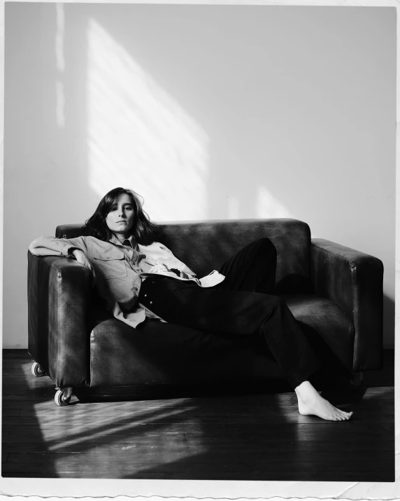 a black and white photo of a woman sitting on a couch, inspired by Sarah Lucas, sun puddle, promo photo, girlboss, jonny greenwood
