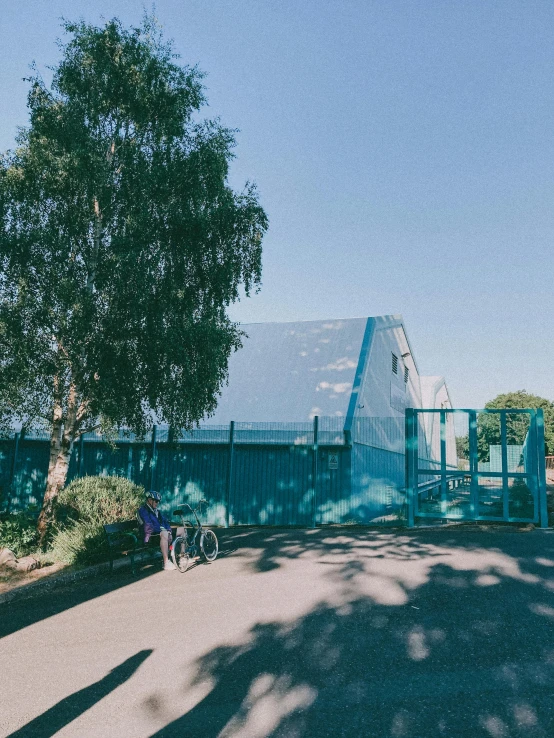 a person riding a bike in front of a building, blue slide park, transparent corrugated glass, trending on vsco, an overgrown library