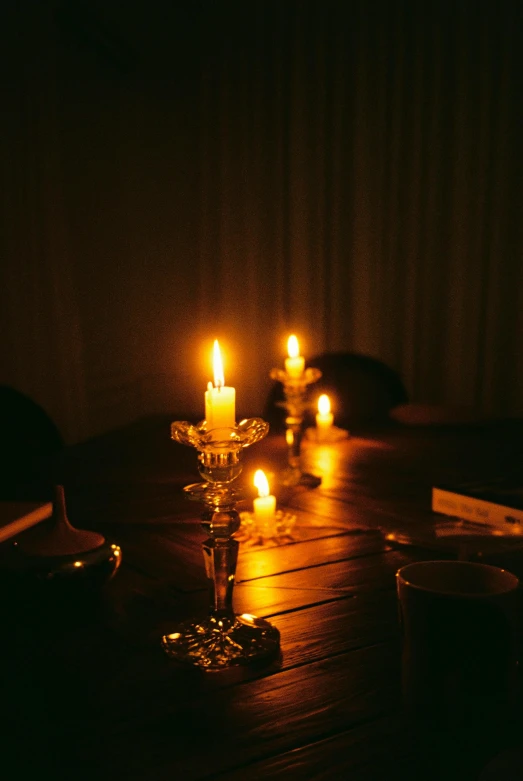 a group of candles sitting on top of a wooden table, by Elsa Bleda, candlelit restaurant table, amanda lilleston, dark hazy room, on a velvet table cloth