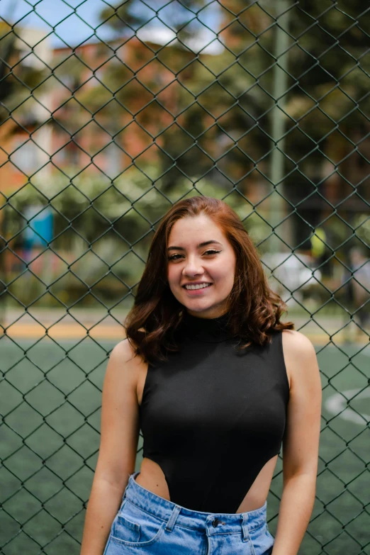 a woman standing in front of a chain link fence, an album cover, pexels contest winner, isabela moner, madly grinning, college, basia tran