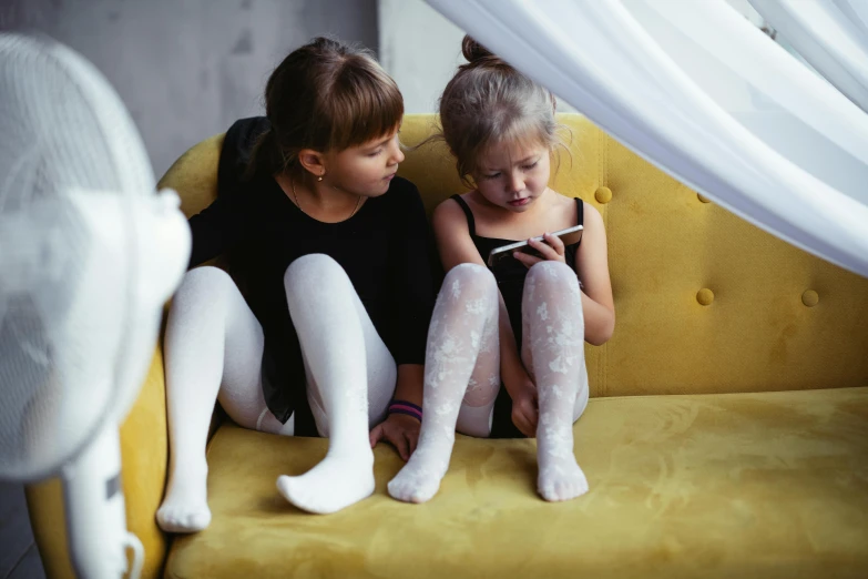 a woman and a little girl sitting on a couch, pexels, white tights, phone photo, cute boys, two girls