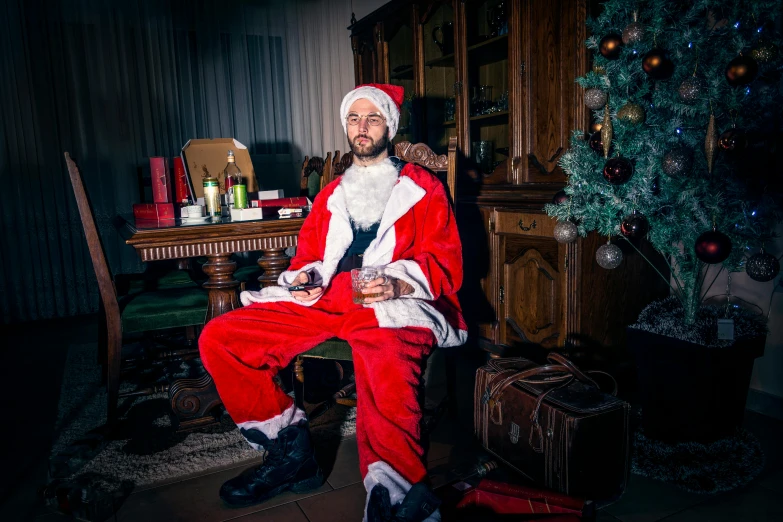 a man in a santa suit sitting in front of a christmas tree, by Julia Pishtar, happening, sebastien chabal, jesus wasted at a party, alessio albi, full costume