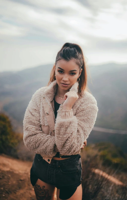 a woman standing on top of a mountain, inspired by Elsa Bleda, trending on pexels, madison beer girl portrait, fur jacket, portrait mode photo, headshot