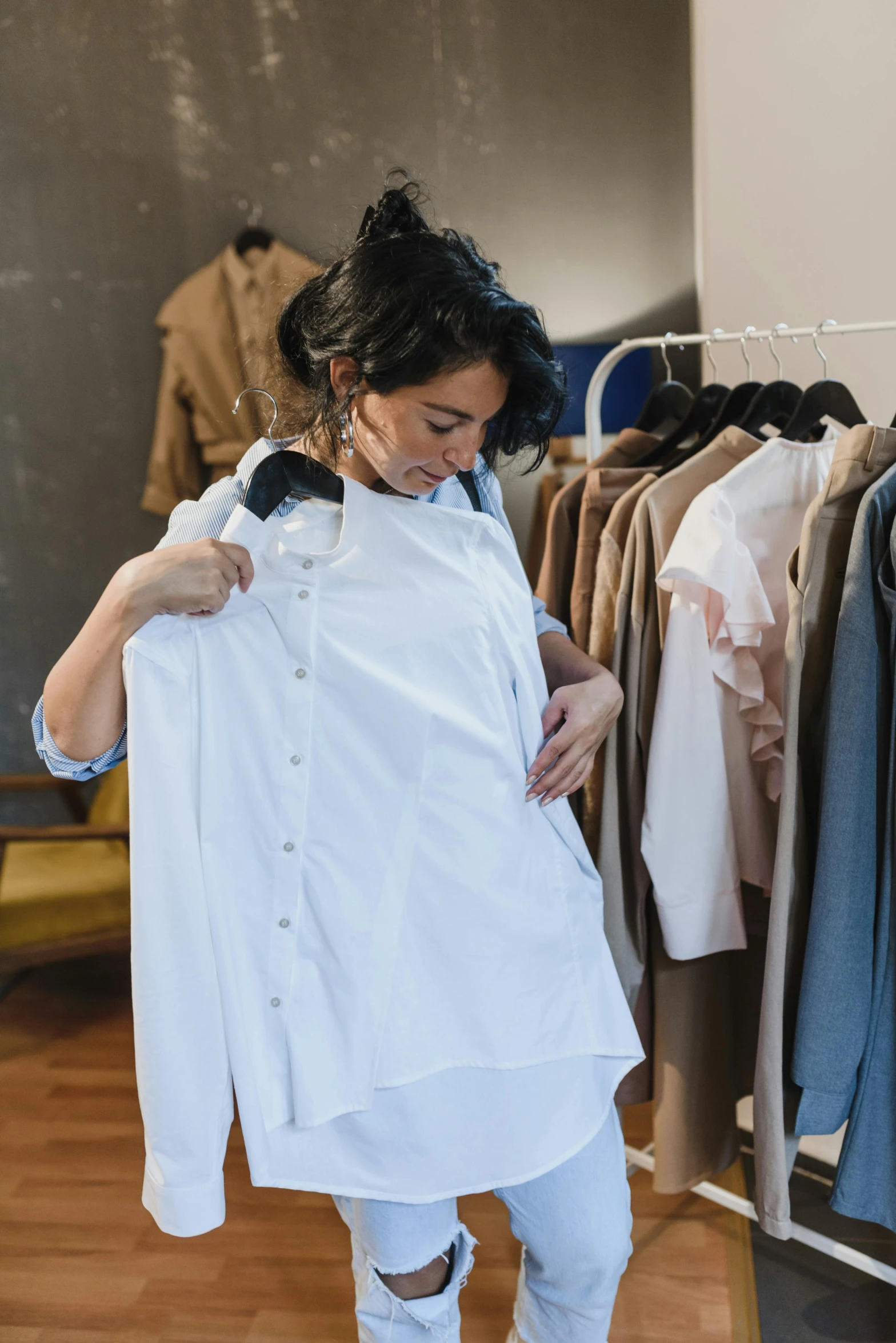 a woman standing in front of a rack of clothes, wearing a white button up shirt, transforming, over-the-shoulder shot, maintenance