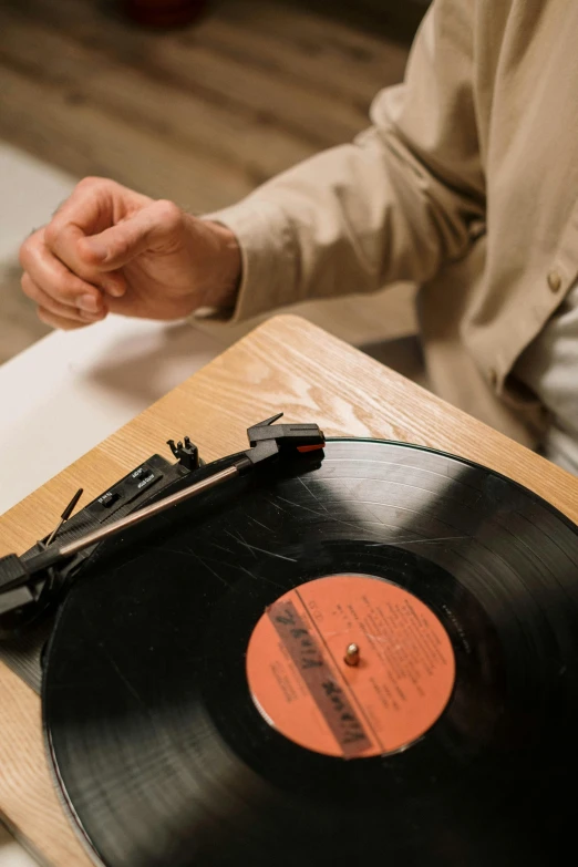 a man sitting at a table with a record on it, zoomed in, wax, shot with sony alpha 1 camera, high quality picture