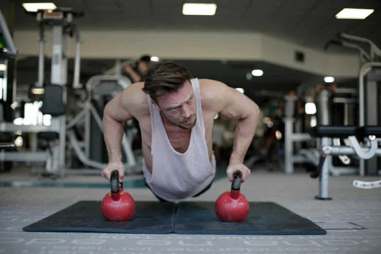 a man doing push ups with kettlebells in a gym, a portrait, by Sam Charles, pexels contest winner, low quality photo, chris evans as a bodybuilder, 30 year old man :: athletic, profile image