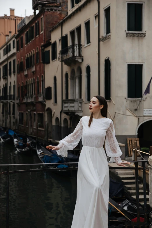 a woman in a white dress standing on a bridge, inspired by Quirizio di Giovanni da Murano, pexels contest winner, renaissance, puff sleeves, gondolas, soft elegant gown, waving robe movement