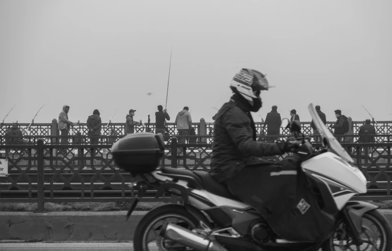 a black and white photo of a person on a motorcycle, by Adam Pijnacker, howrah bridge, distant hooded figures, lots of people, people are wearing masks