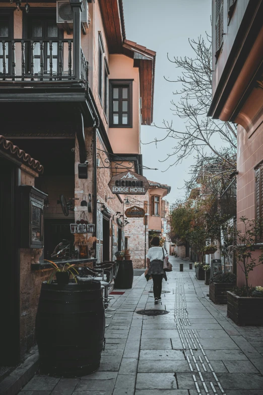 a person walking down a street holding an umbrella, old buildings, byzantine, unsplash photography, multiple stories