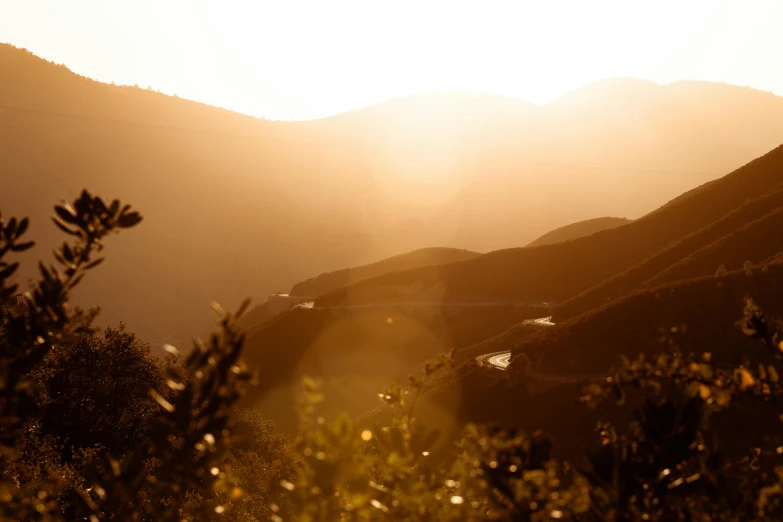 the sun is setting over a mountain range, by Alexis Grimou, fan favorite, ambient amber light, golden hour photograph, brown