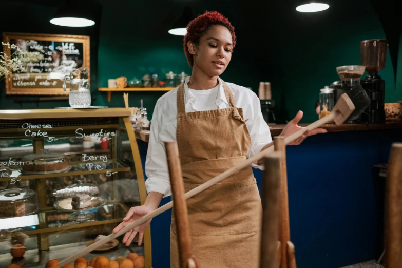 a woman that is standing in front of a counter, inspired by Richmond Barthé, pexels contest winner, wooden staff, nathalie emmanuel, bakery, mechanics