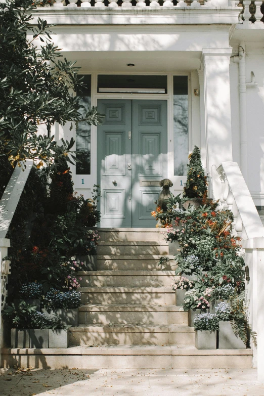 a white house with a blue front door, by Carey Morris, pexels contest winner, arts and crafts movement, outdoor staircase, grey, flower decorations, muted pastels