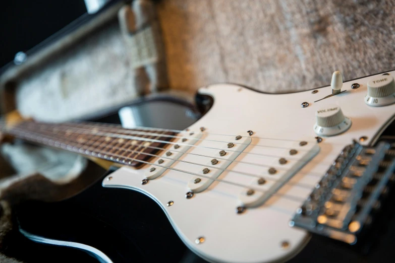 a close up of a guitar in a case, by Gavin Nolan, unsplash, holding a silver electric guitar, delightful surroundings, fender stratocaster, on display ”