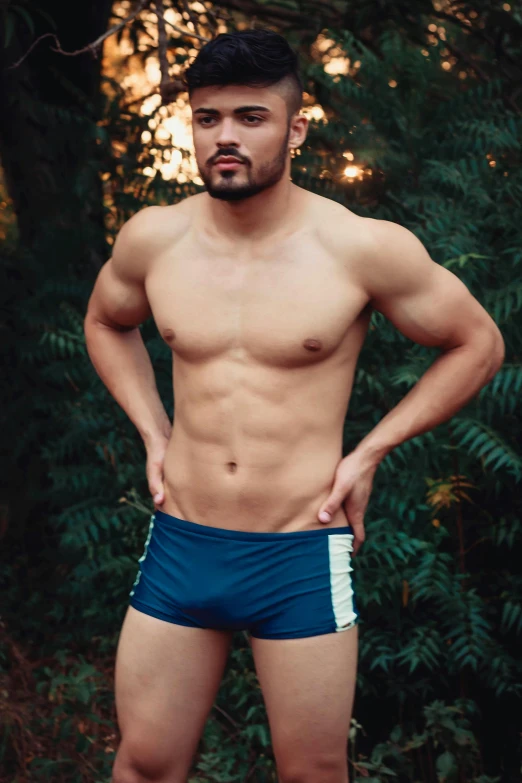 a shirtless man standing with his hands on his hips, a colorized photo, by Adam Dario Keel, sport bra and dark blue shorts, darren quach, profile image, vines