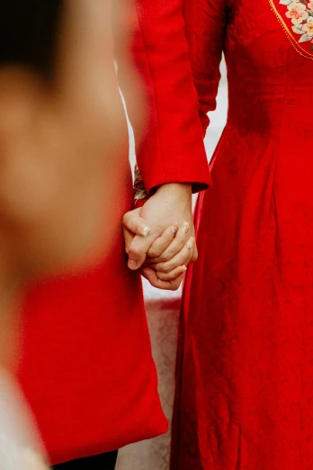 a close up of two people holding hands, by Julia Pishtar, symbolism, wearing red formal attire, ao dai, lgbt, sisters