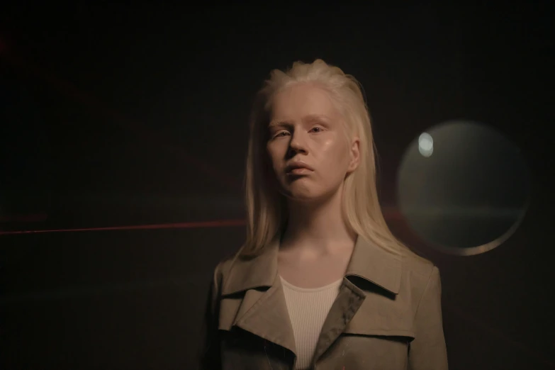 a woman with blonde hair standing in a dark room, a hologram, inspired by Vanessa Beecroft, albino dwarf, shot on anamorphic lenses, portrait of a teen robot, film still promotional image