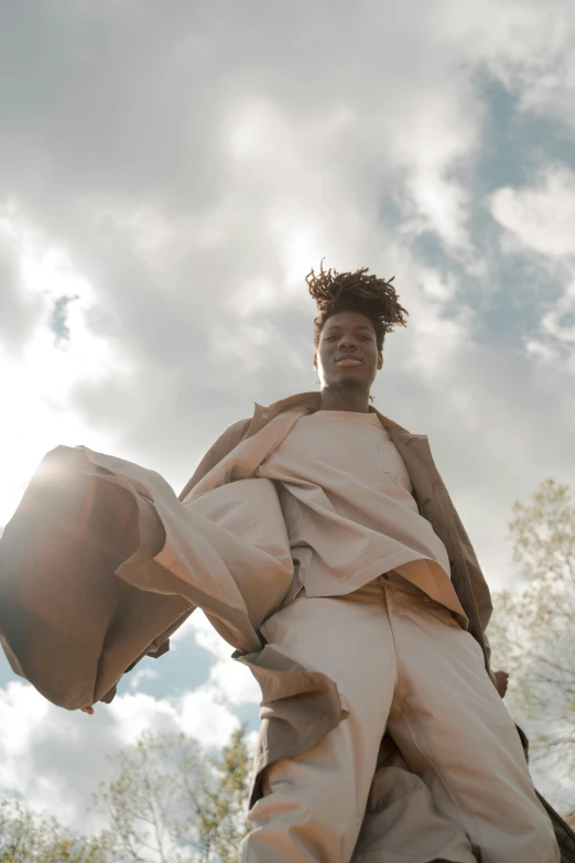 a man standing on top of a pile of luggage, trending on unsplash, afrofuturism, flowy hair standing on a rock, brown robes, ( ( theatrical ) ), young thug