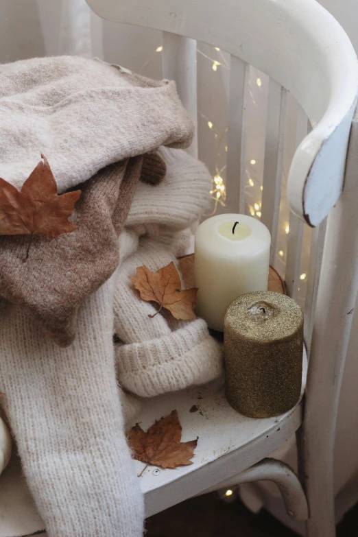 a pile of sweaters sitting on top of a white chair, a still life, trending on pexels, romanticism, lantern candle, autum, led, bath