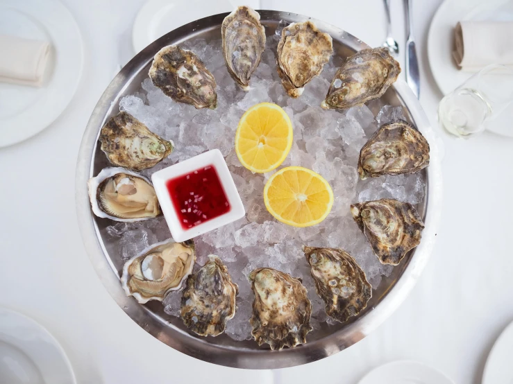 a platter of oysters with lemon slices and ketchup, a portrait, pexels, jen atkin, 8l, 2000s photo, restaurant