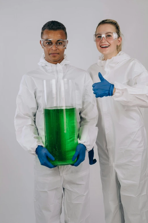 a couple of people standing next to each other, beakers full of liquid, giving a thumbs up to the camera, wearing green, 🚀🌈🤩