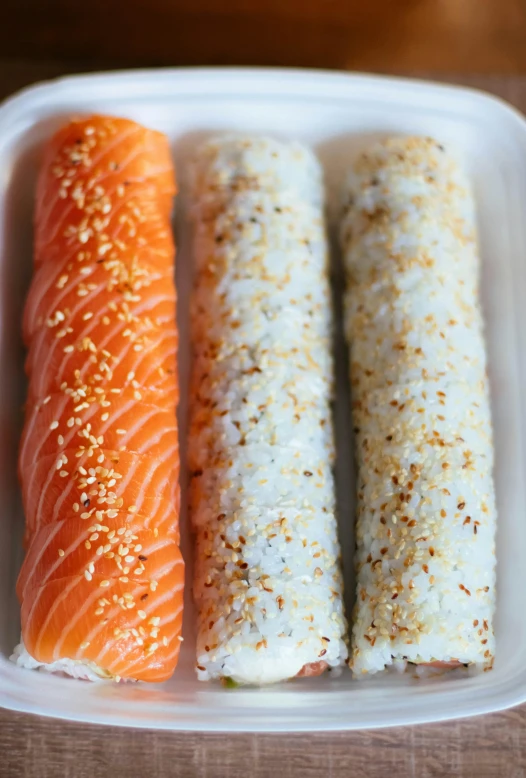 three sushi rolls in a styrofoam container, inspired by Maki Haku, unsplash, mingei, bagels, shimmers, white and orange, 2000s photo