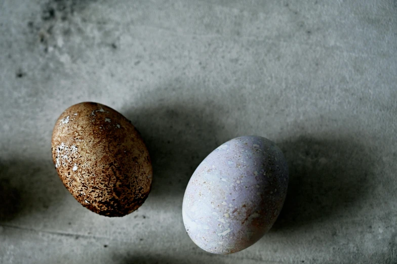 three eggs sitting next to each other on a table, sōsaku hanga, concrete, multi - coloured, small