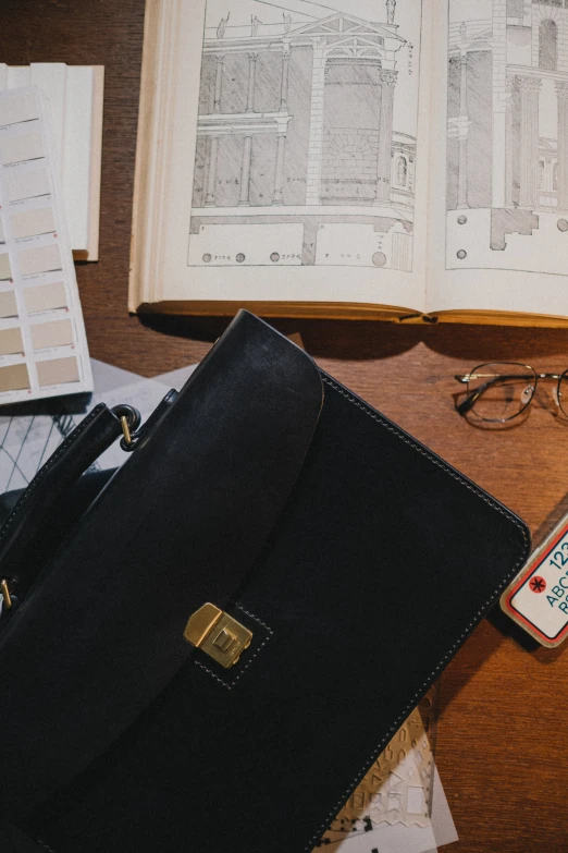 a black briefcase sitting on top of a wooden table, a picture, trending on pexels, modernism, field notes, flatlay book collection, thumbnail, architect