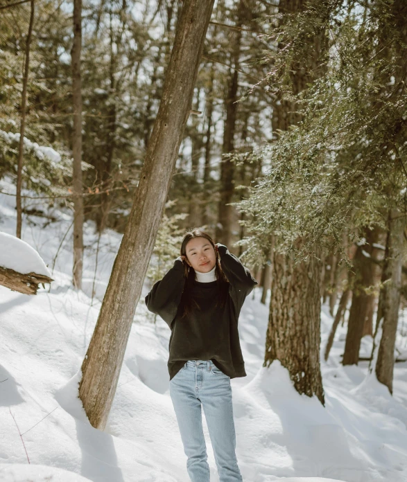 a woman riding a snowboard down a snow covered slope, an album cover, by Emma Andijewska, pexels contest winner, happening, walking around in a forest, black sweater, asian woman, simple aesthetic